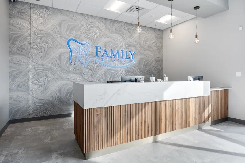 The reception desk at NS Family Dental, with the practice logo on the marble feature wall